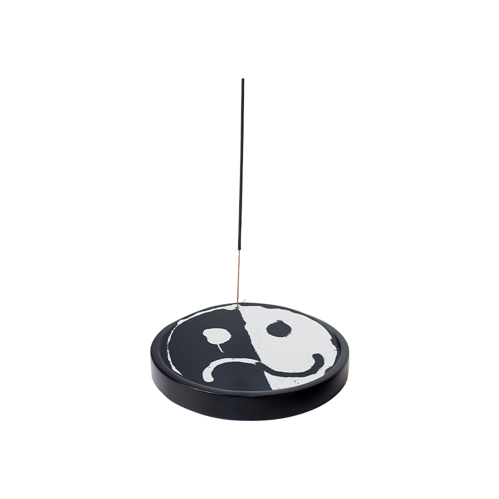 Yin-yang symbol incense holder with a thin stick inserted.