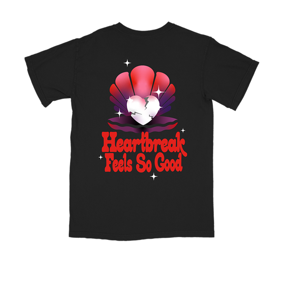 Black t-shirt with a colorful graphic design featuring a broken heart in a shell and text reading ’Heartbreak Feels So Good’.